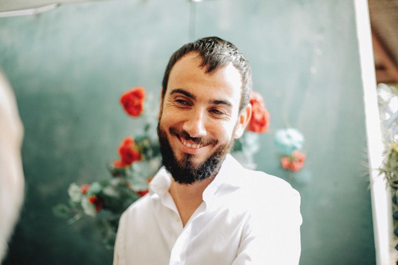 Bright portrait with red flowers in background showing genuine smile.