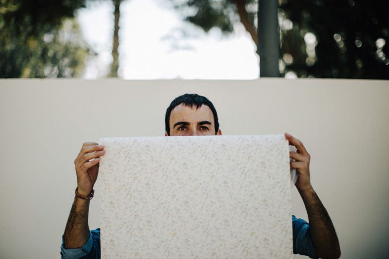 Person holding up a large white textured panel outdoors.