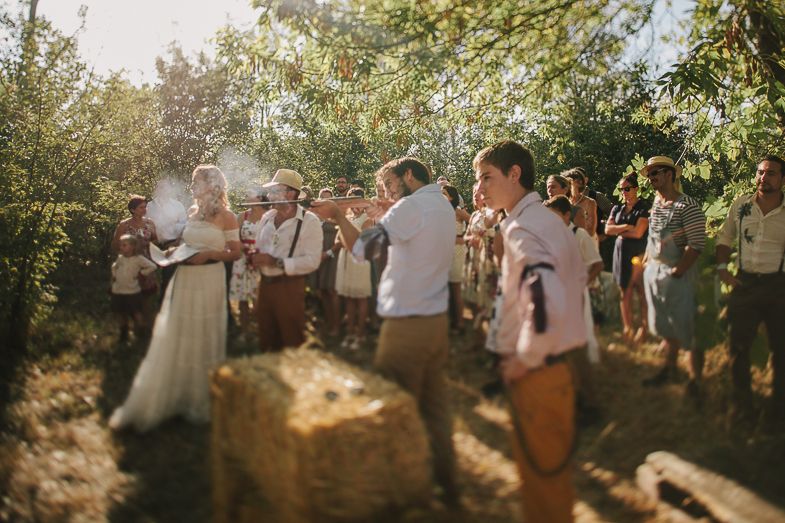 Guests celebrating at a rustic outdoor wedding reception with natural lighting.