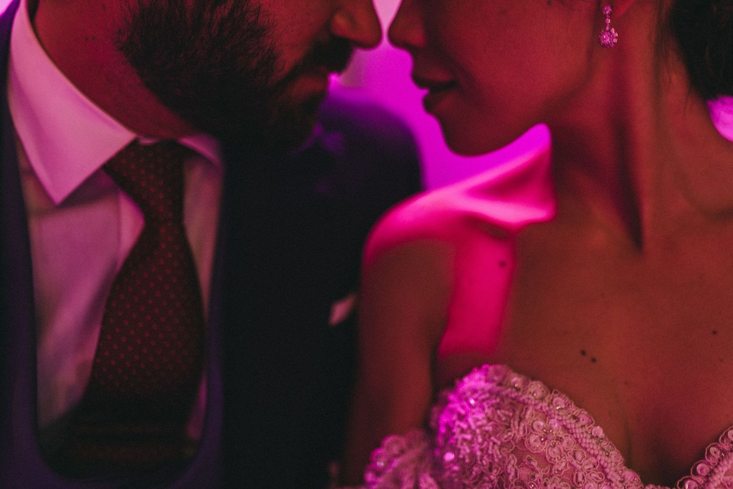 Intimate close-up silhouette against pink lighting at an elegant evening celebration.