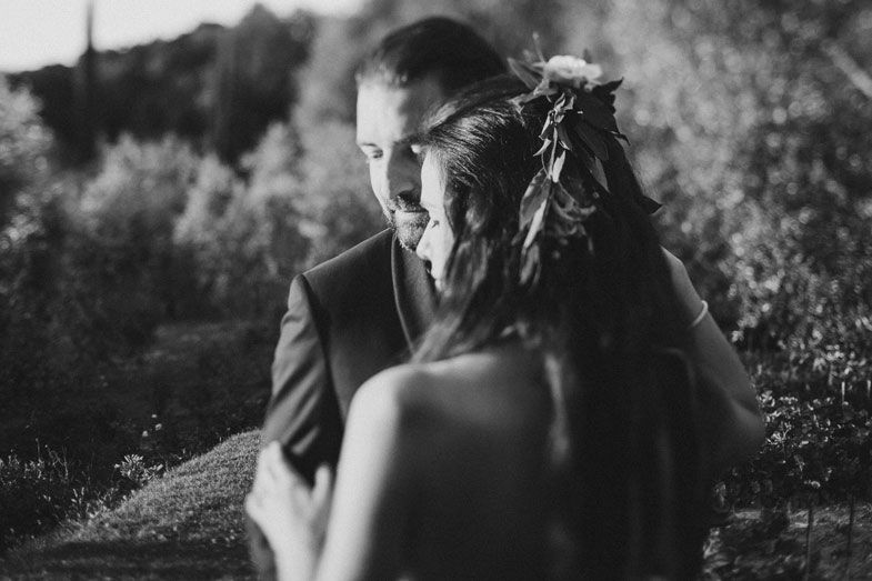 A dramatic black and white wedding portrait captured in an outdoor setting.