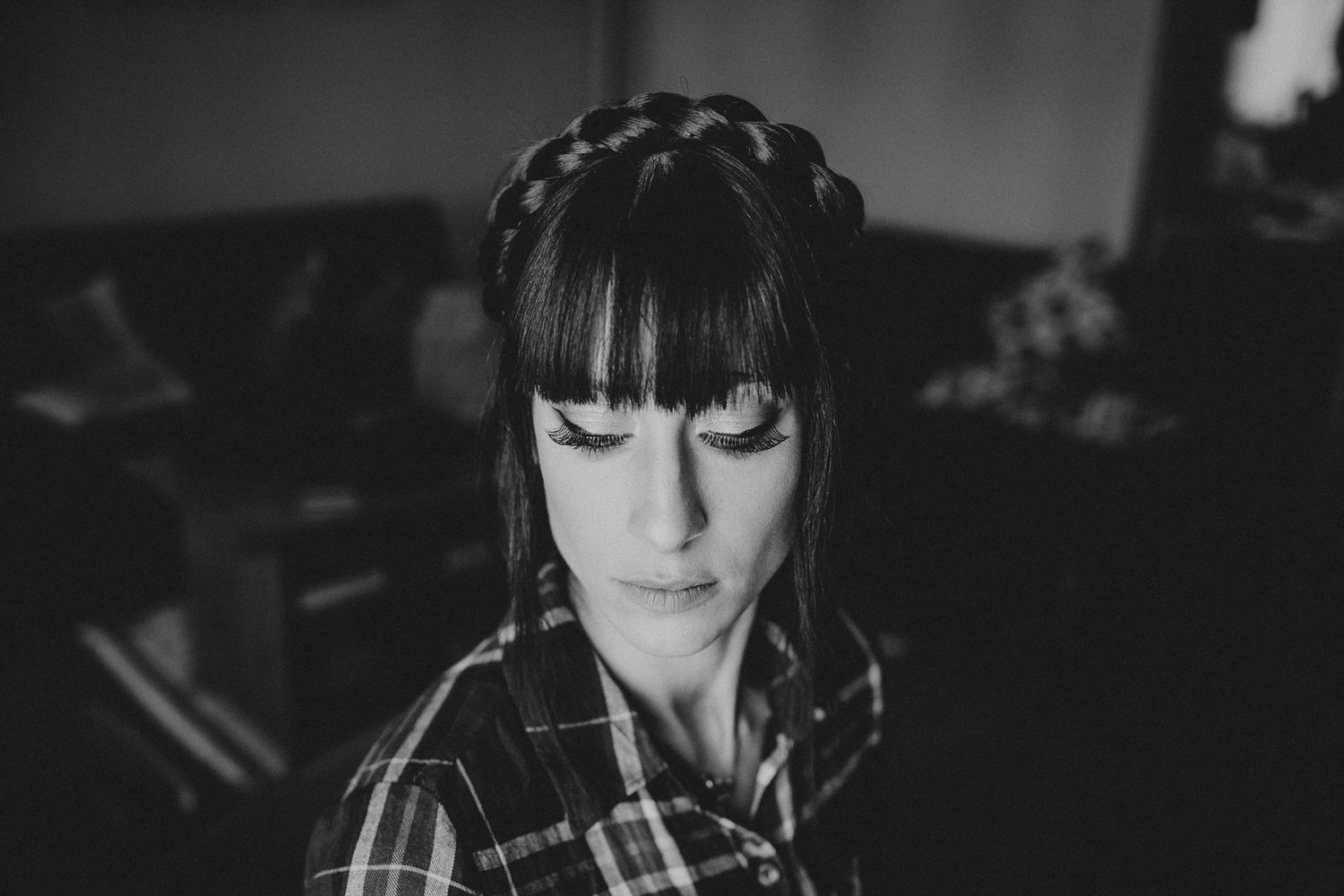 Dramatic black and white portrait with intricate braided hairstyle in low light.