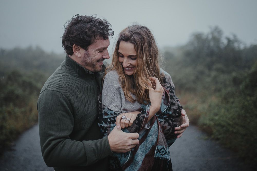 A joyful couple sharing laughter while embracing on a misty path outdoors.