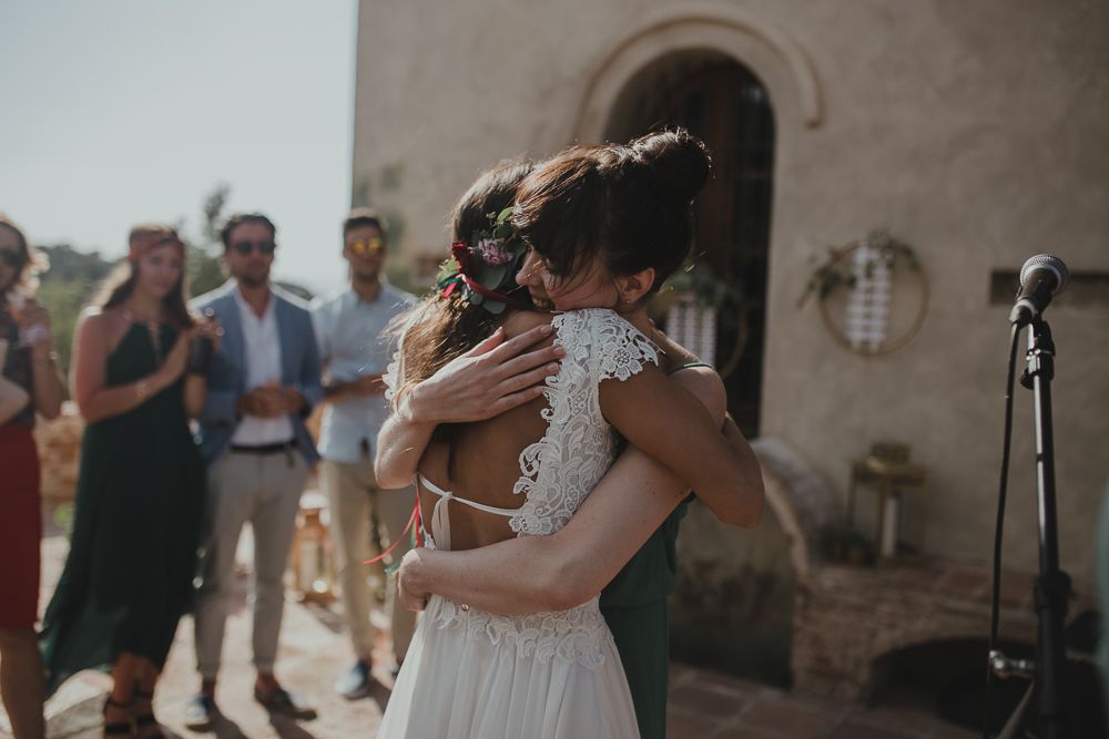 Emotional embrace shared during wedding celebration at stone building venue.