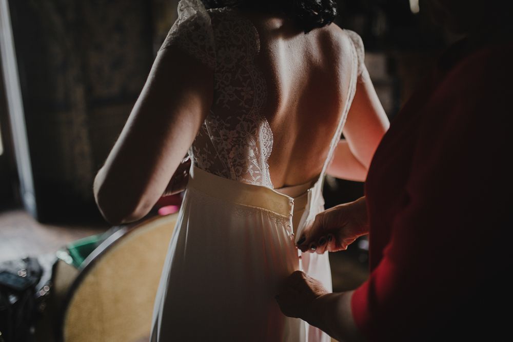 Back view of dress being fastened in intimate getting ready moment.