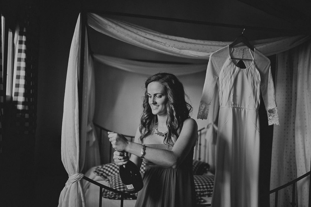 Black and white photo showing dress preparations in a room with soft window light.