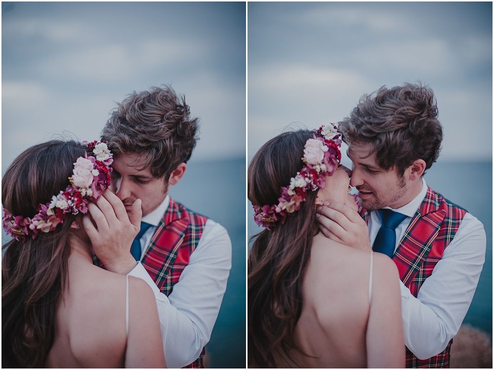 Intimate romantic moment captured between couple wearing plaid and floral crown against moody sky.
