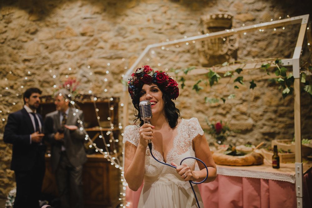 Wedding celebration with string lights and rustic stone wall backdrop.