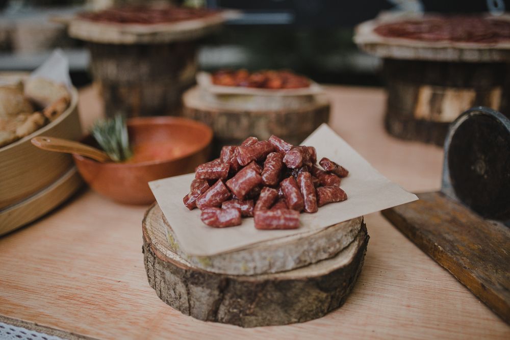 Cured meats displayed on rustic wood slices at a charcuterie station.