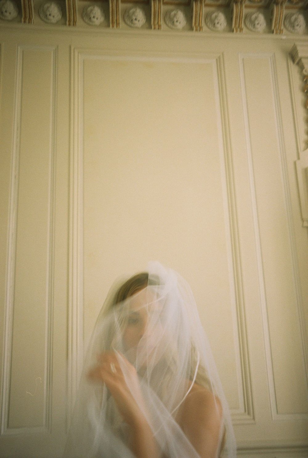 Artistic sequence of a bridal veil movement against cream colored wall panels.