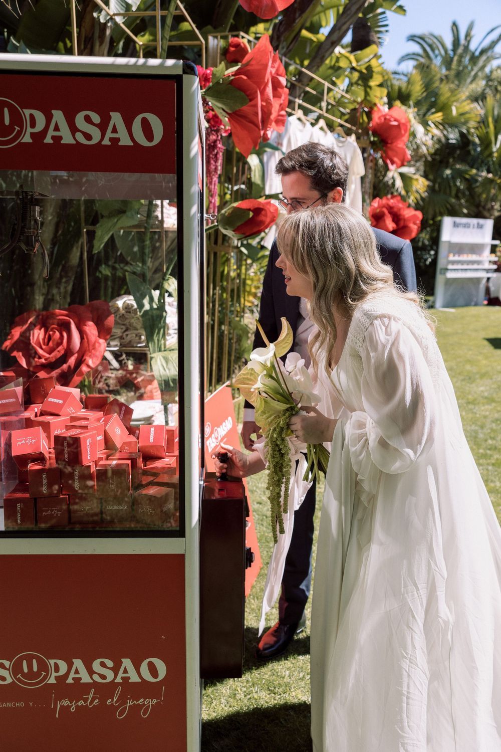 A wedding guest examines treats at a red Pasao dessert cart decorated with roses.