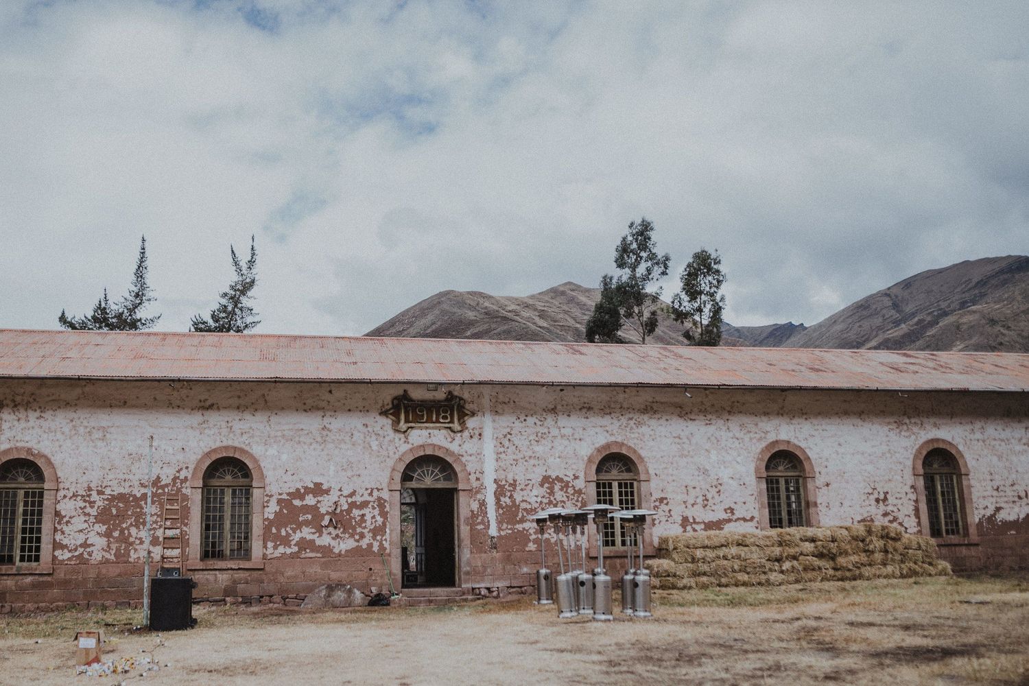 Historic colonial-style building with arched windows and deteriorating facade in mountain setting.
