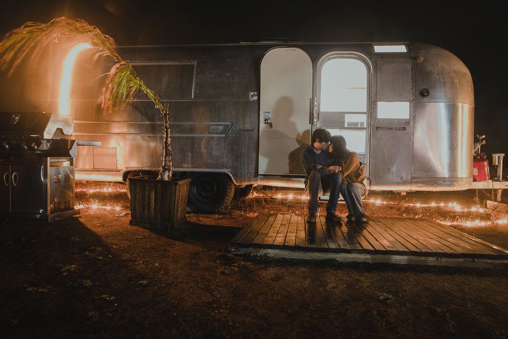 Sparklers create magical light trails against a silver Airstream trailer at night.