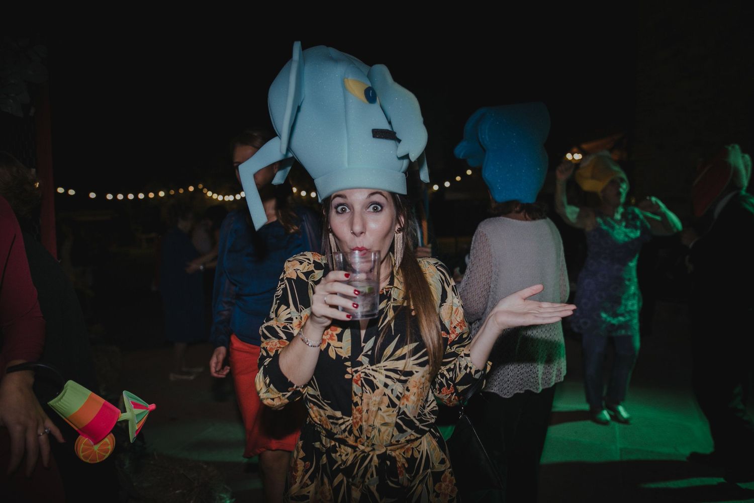 Party guest in elephant hat costume enjoying festivities at nighttime event.
