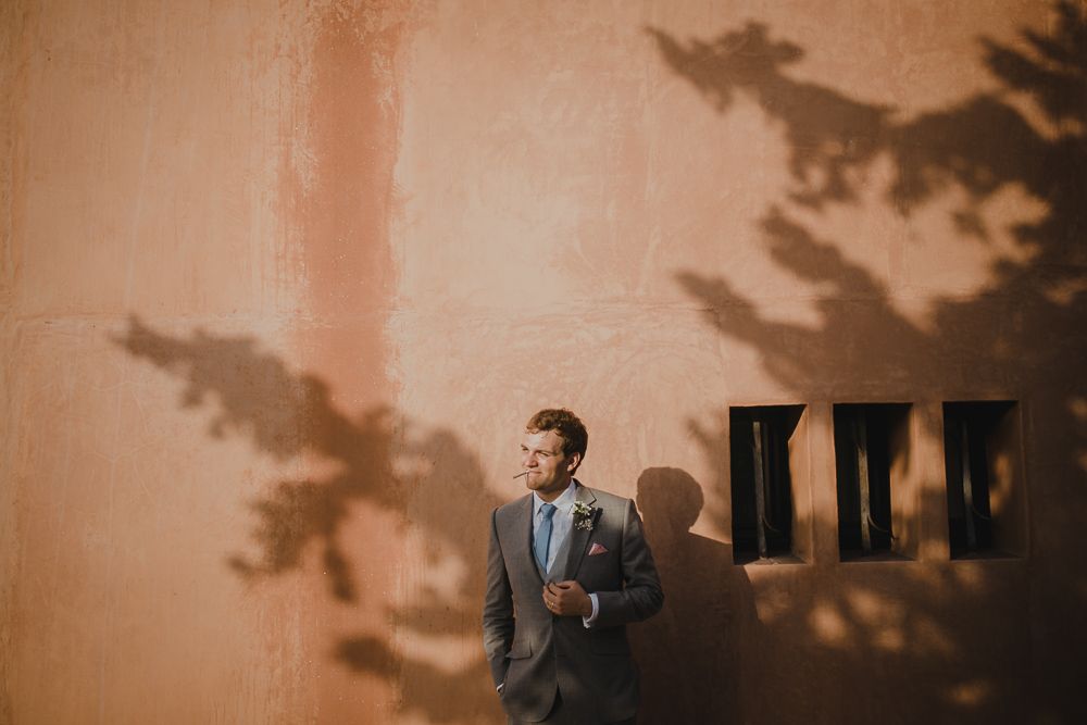Artistic portrait with dramatic tree shadows cast on salmon-colored wall.