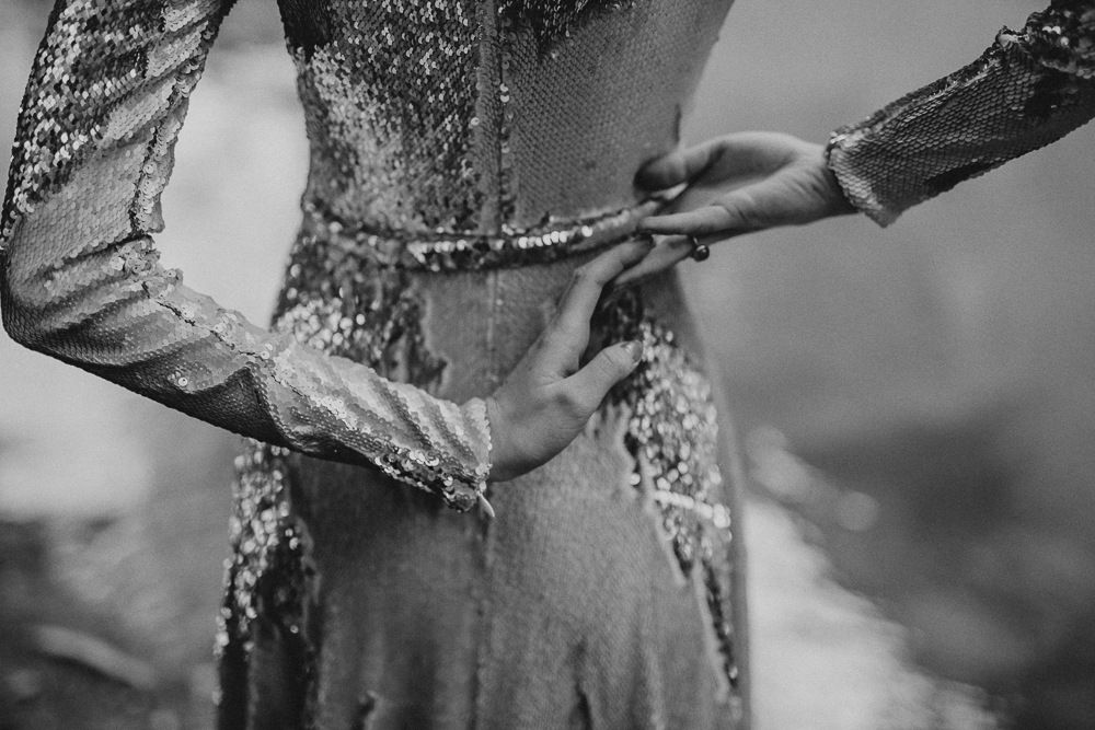 Close-up black and white image showing hands adjusting a sequined dress.