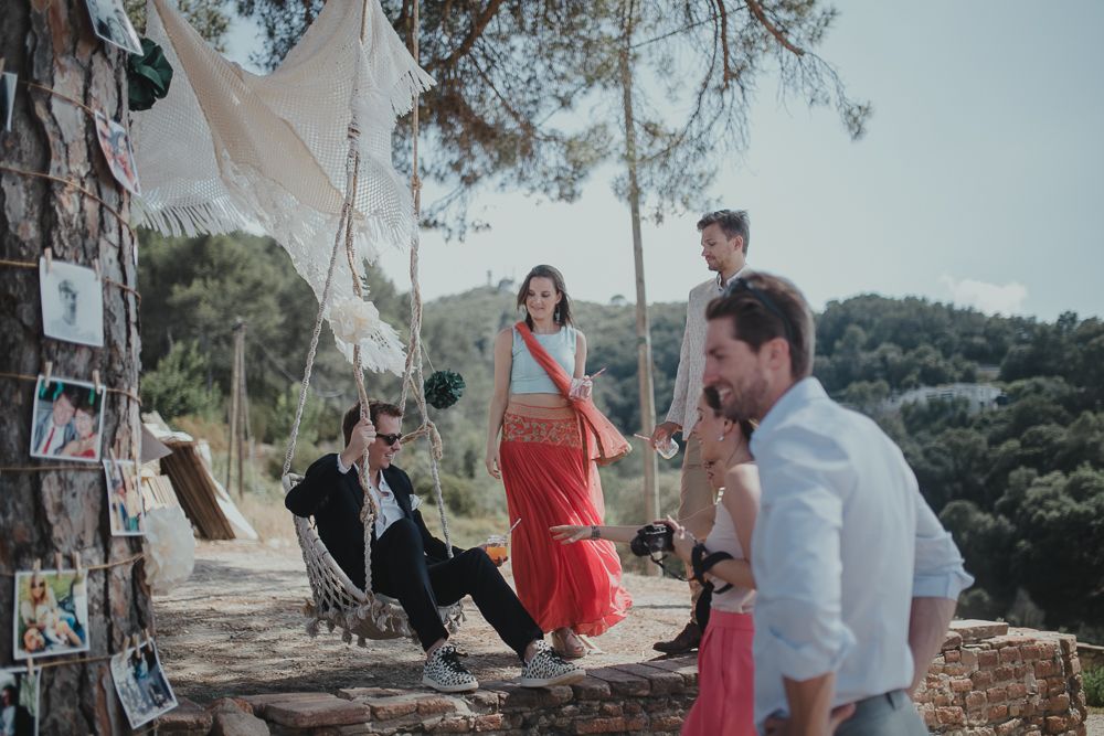 Outdoor gathering with hanging decorations and people relaxing in a scenic hilltop setting.