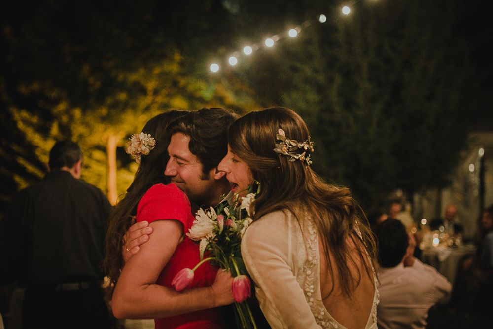 Guests celebrate at an intimate outdoor evening wedding reception under twinkling lights.