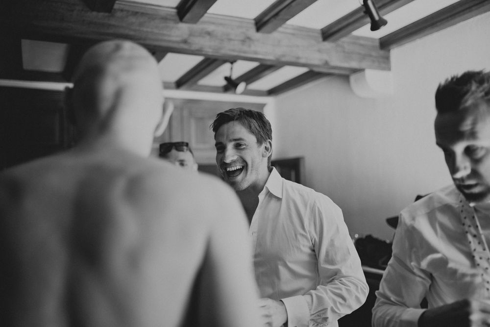 People laughing and getting ready in a room with exposed ceiling beams.