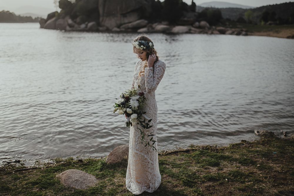 Elegant bridal portrait by the waterfront with mountains and rocks in the background.
