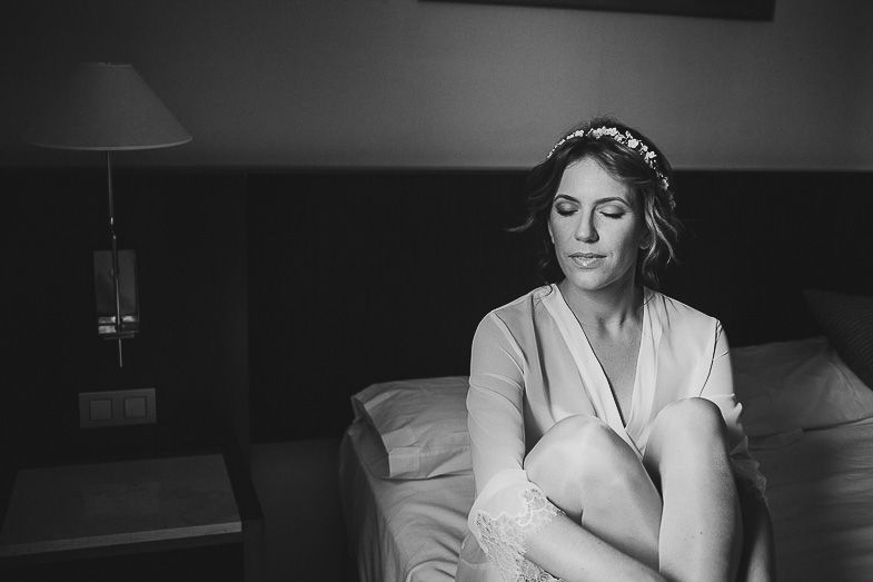 Black and white photograph capturing quiet moment in bedroom with lamp.