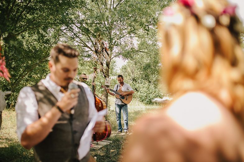 A guitarist plays music in the background during an outdoor wedding ceremony.