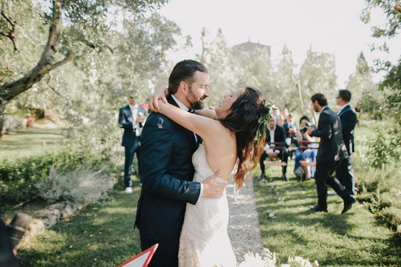 Wedding guests celebrate with the newlyweds during an outdoor garden reception.