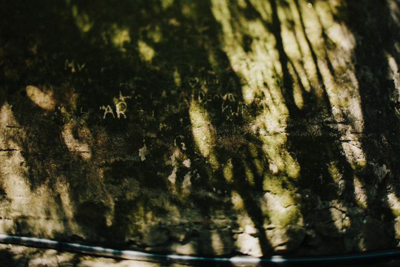 Dappled sunlight creates abstract patterns on a weathered stone wall.