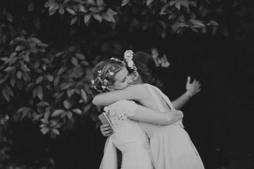 Black and white emotional embrace captured during wedding celebration outdoors.
