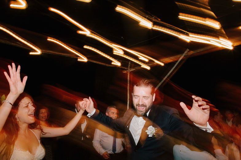 Wedding reception guests dancing enthusiastically under dramatic lighting.