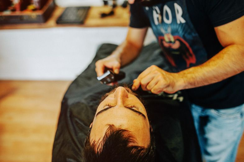 Overhead view of a client getting a professional shave at a barbershop.