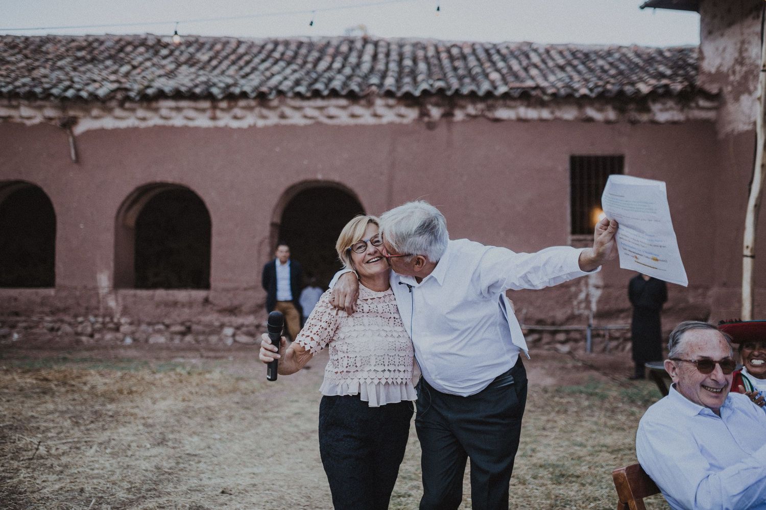 Two people sharing a joyful moment while dancing together at a rustic venue.