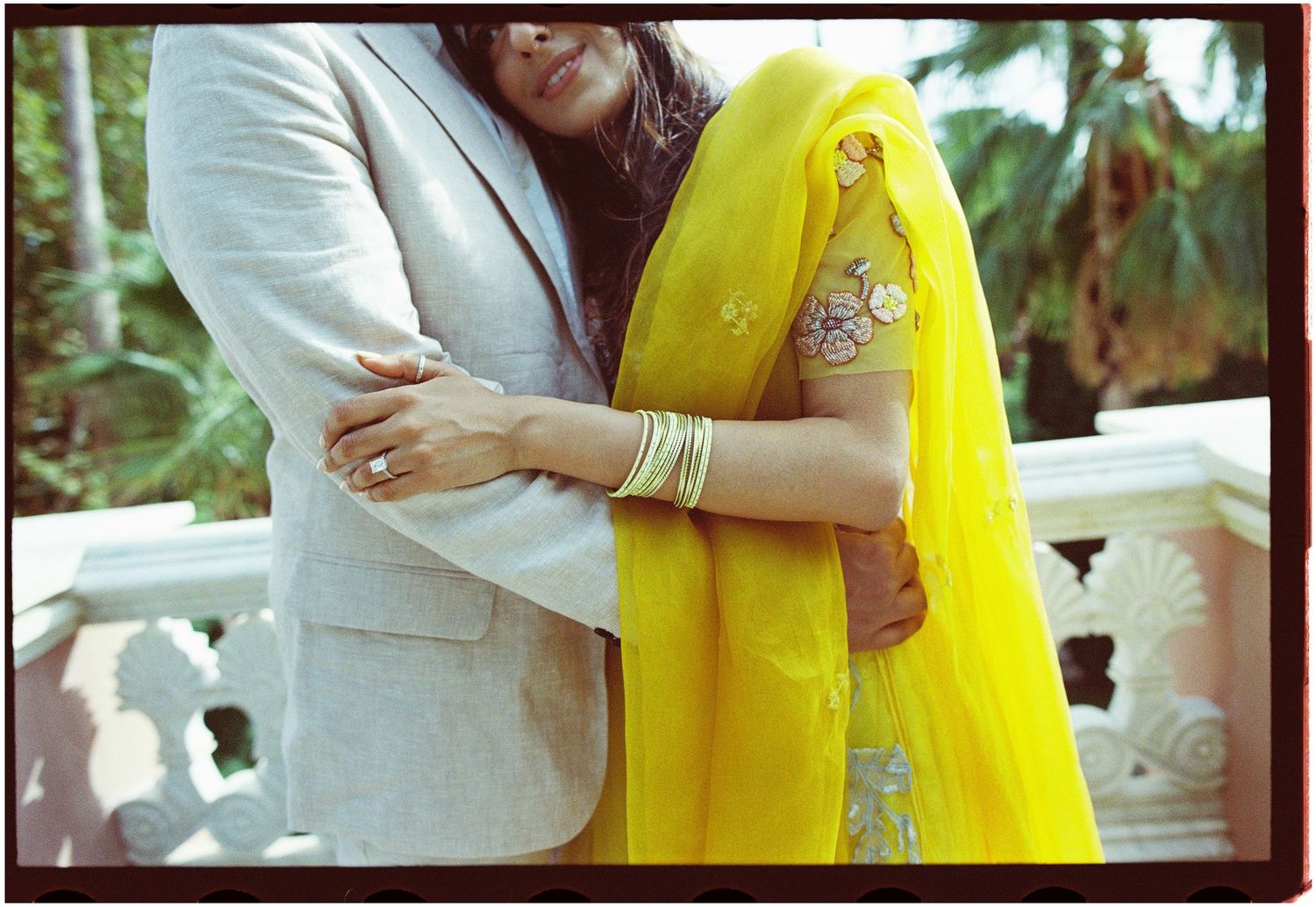 Film detail of Elina and Jag embracing, with yellow fabric and gold bangles.