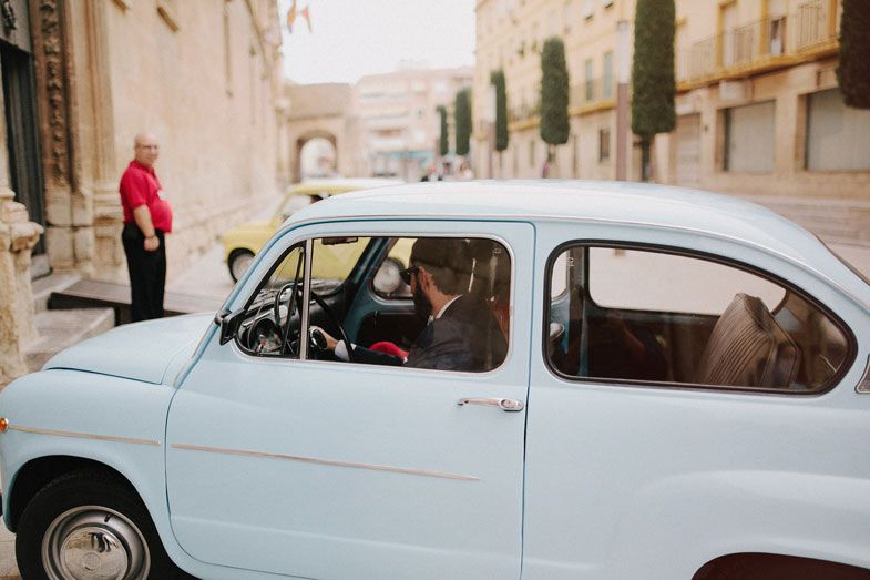 Light blue vintage Fiat 600 parked on European street with stone buildings.