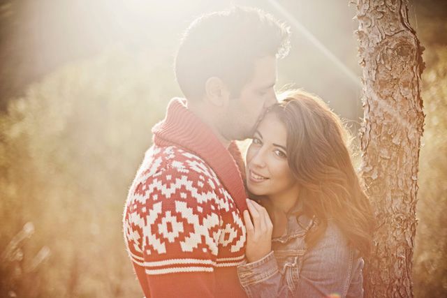 Romantic couple in seasonal clothing share a tender moment in golden backlight.