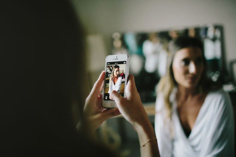 Someone taking a photo on a smartphone during a wedding preparation session.