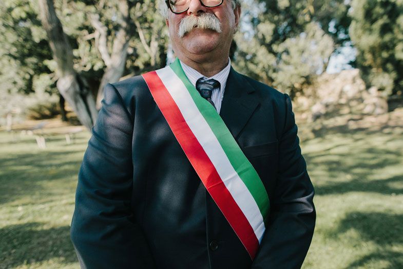 Official wearing traditional Italian sash at outdoor wedding ceremony.