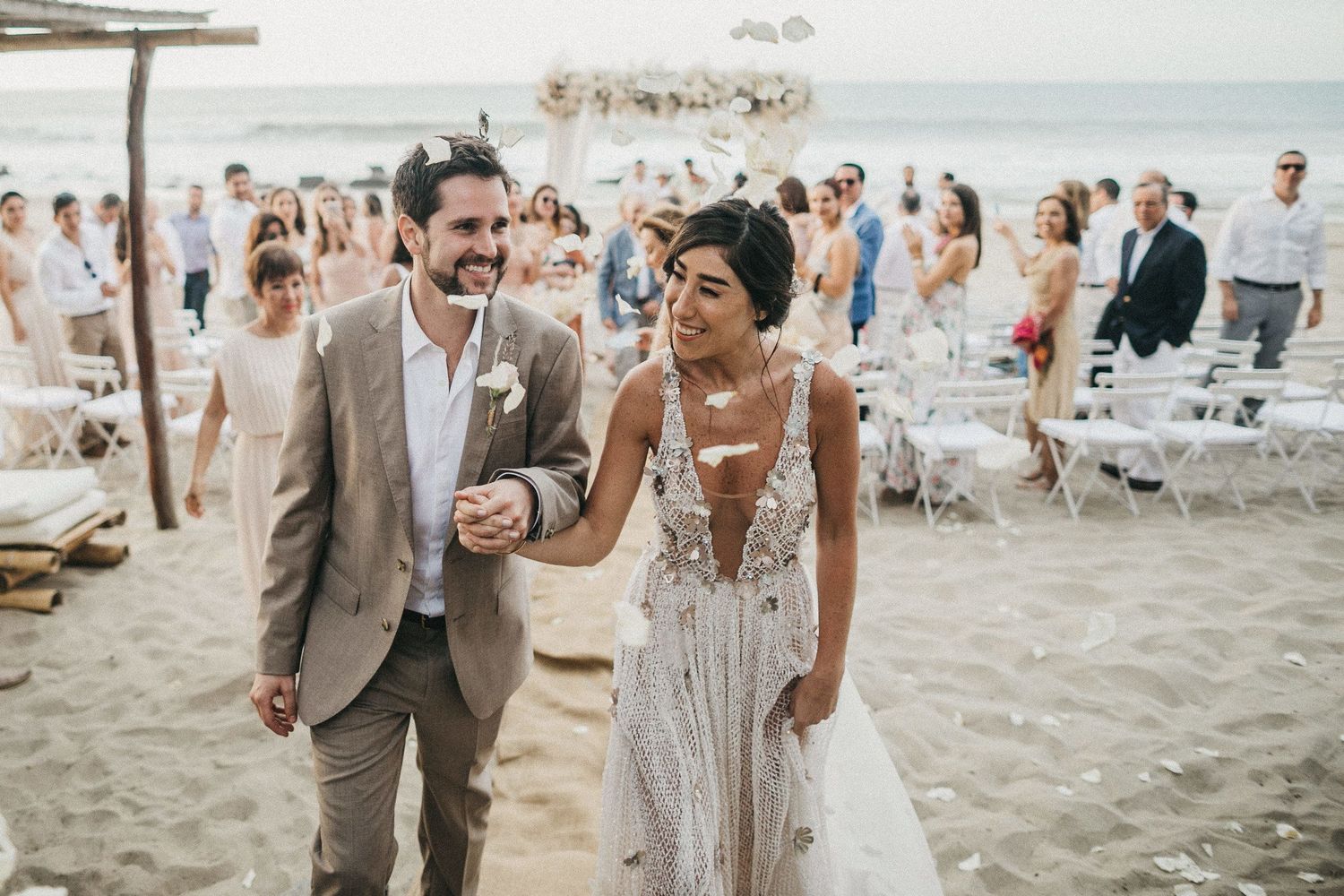Newlyweds share a joyful moment walking on the beach during their destination wedding.