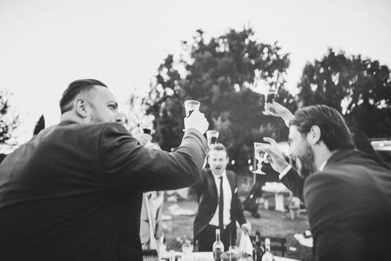 Black and white photo of guests toasting at an outdoor celebration.