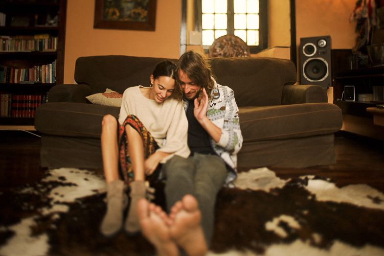 A cozy living room scene on a gray couch with bookshelves and speakers in the background.
