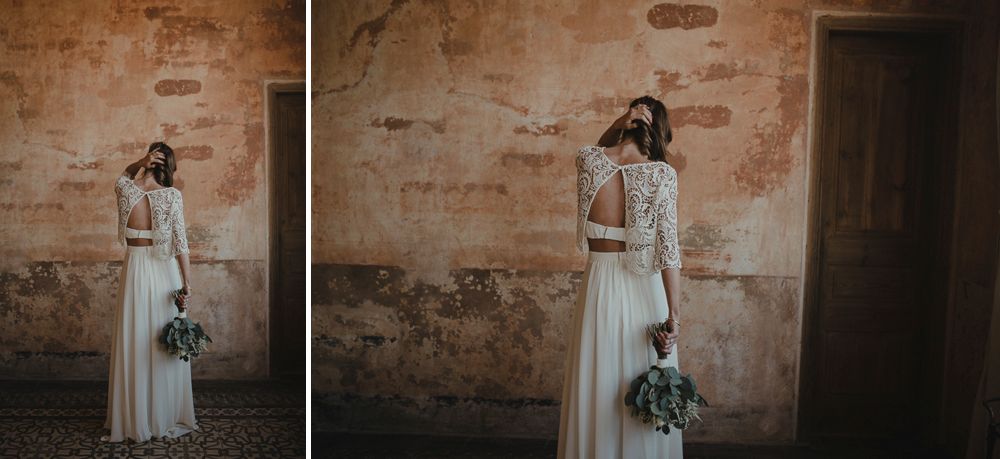 Elegant white wedding dress against a rustic stone wall backdrop with vintage styling.