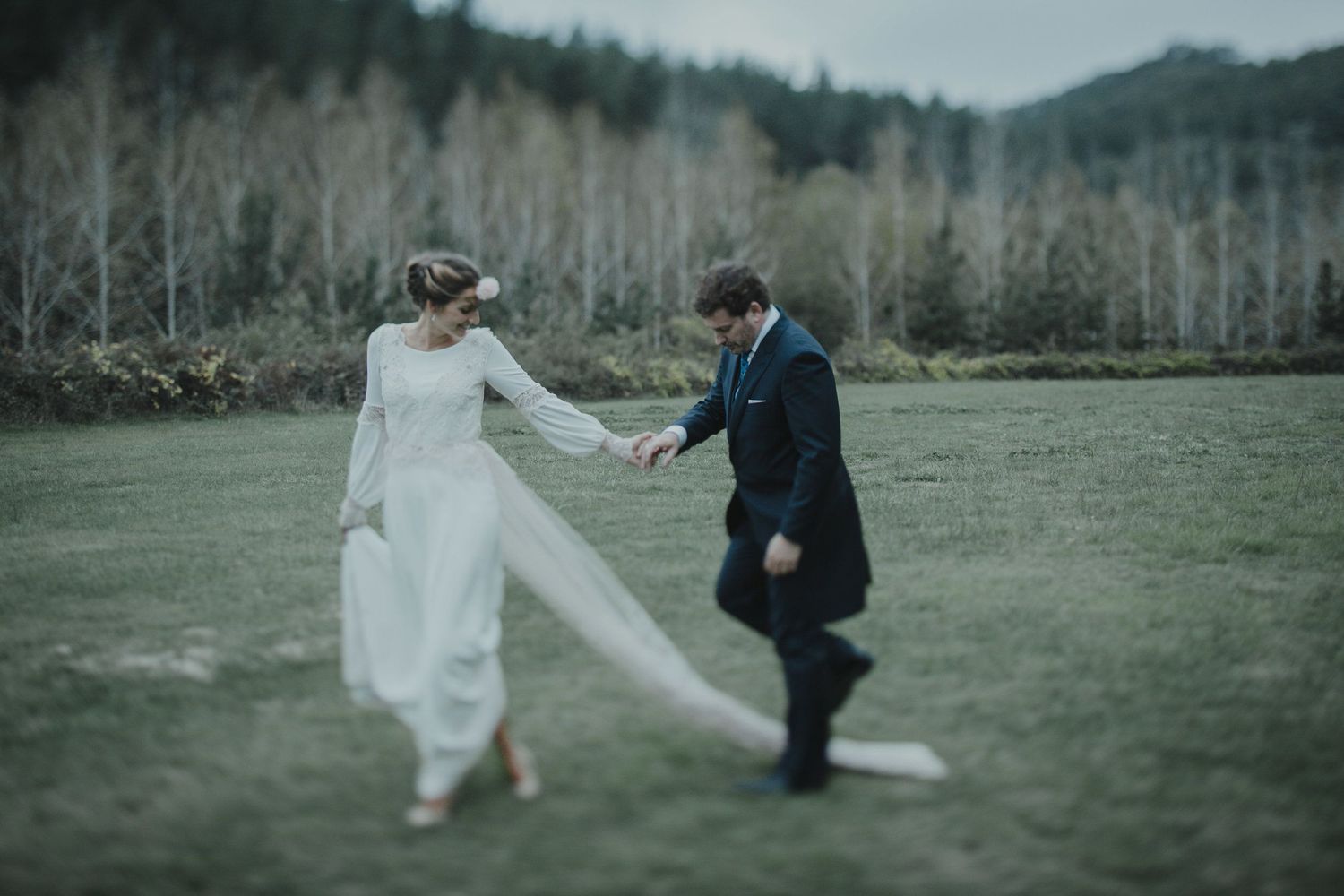 A couple dancing together in formal attire across a misty field.