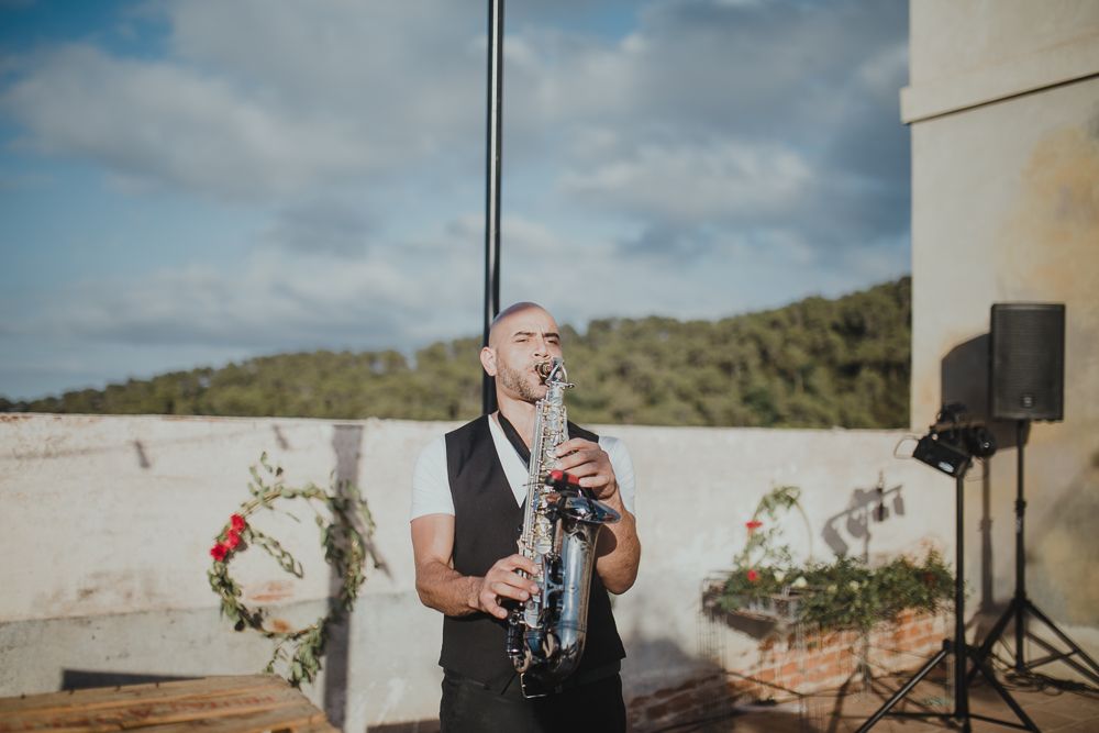 Musician playing clarinet at outdoor event with scenic mountain backdrop.