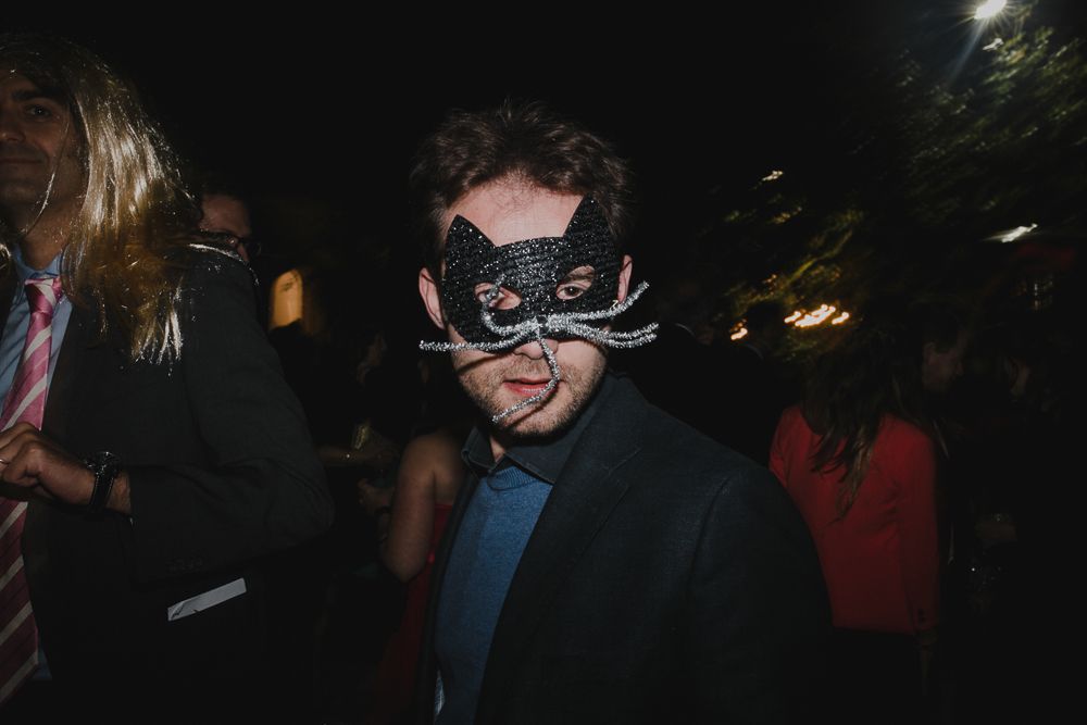 Guest wearing an elegant black masquerade mask at a nighttime celebration.