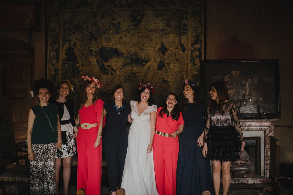 Wedding party photo featuring bridesmaids in various colored dresses against vintage decor.