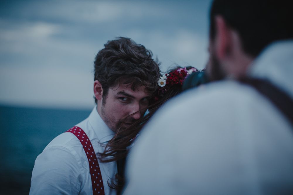 Two figures share an intimate moment against a moody ocean backdrop.