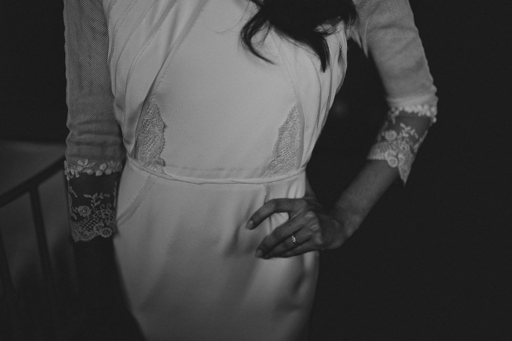 Side view of fitted wedding dress showing lace sleeve detail and elegant silhouette.