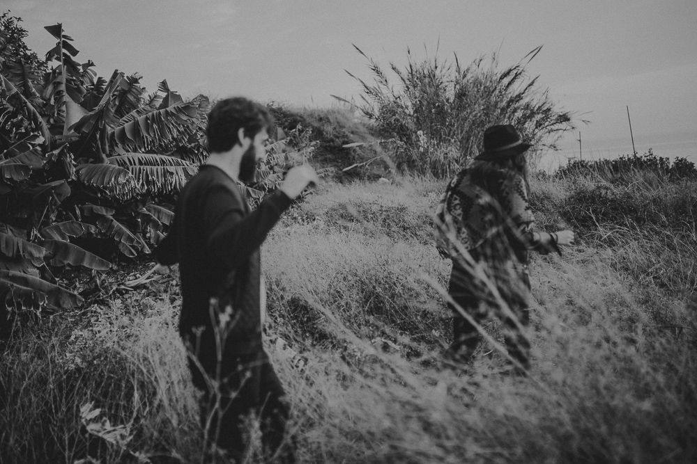 Artistic black and white photo of two people in a wild grassy field.