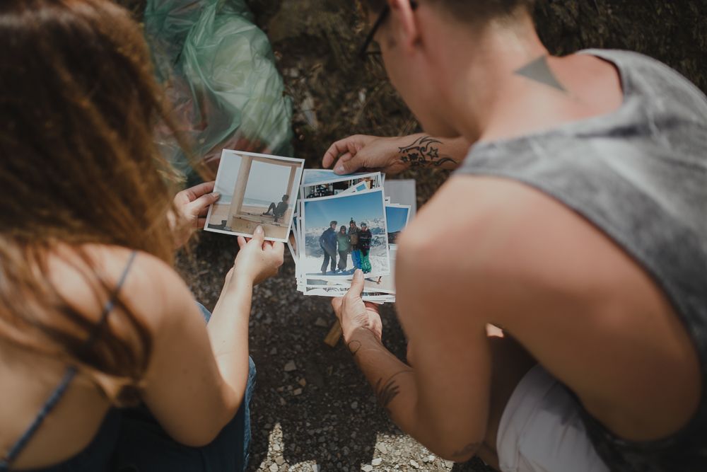 Two people looking at photographs together outdoors in a candid moment.