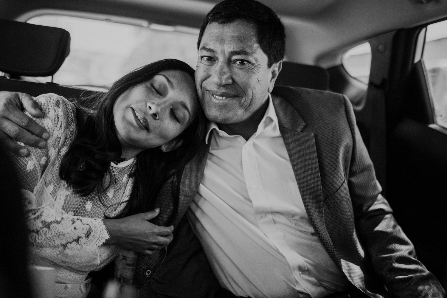 Black and white photo of couple resting in back seat of car.